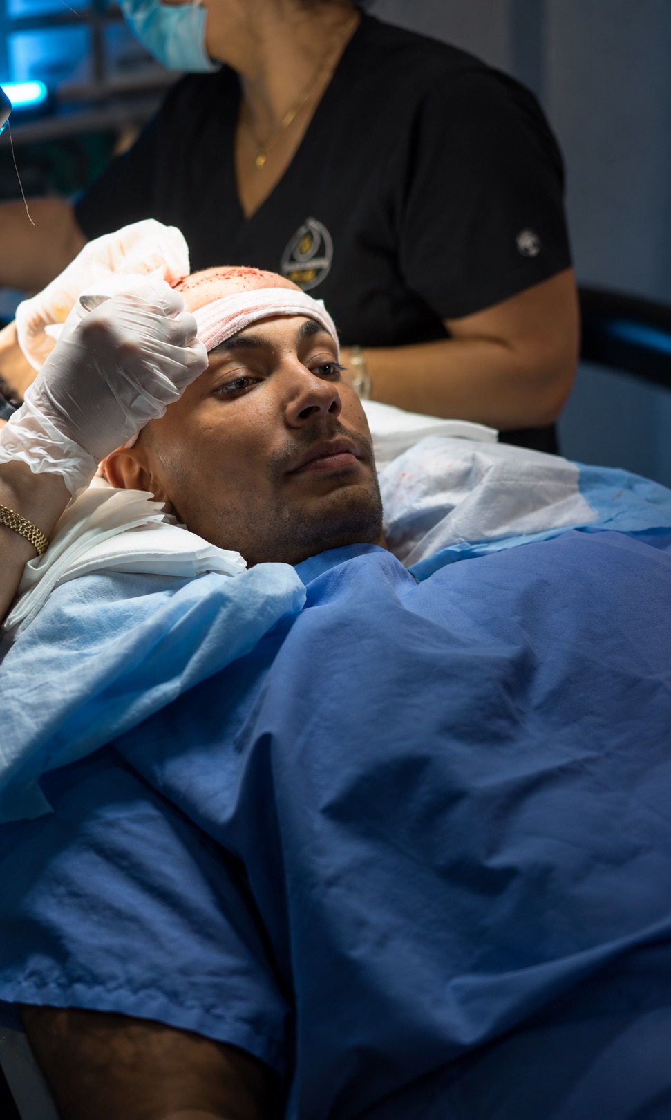 Patient reclining calmly during a hair transplant procedure as gloved clinicians work on the recipient area