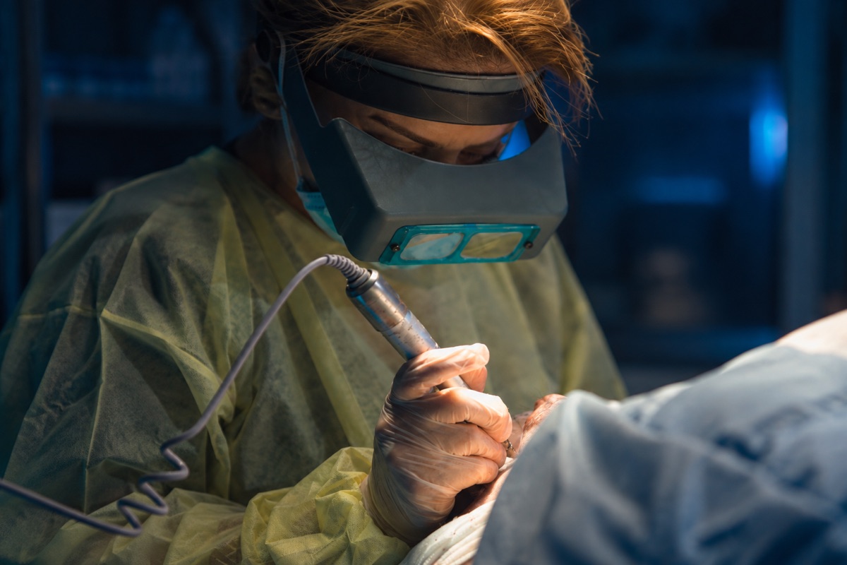 Clinician wearing magnifying loupes using a fine handheld instrument during a transplant procedure