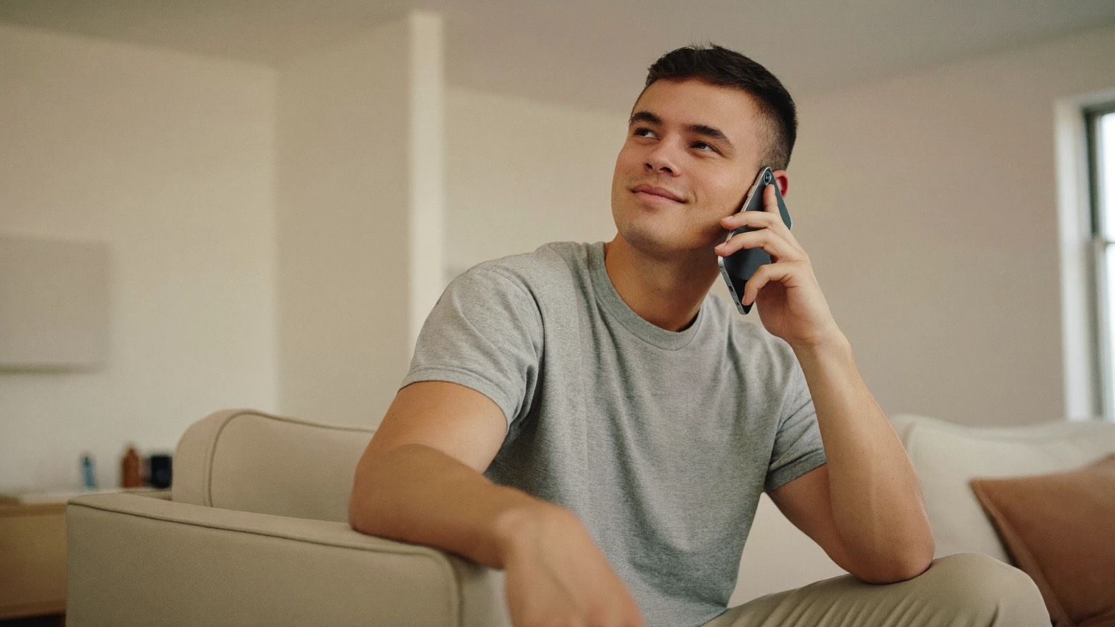 Man sitting on a sofa at home talking on the phone to his clinic about a concern after a hair transplant